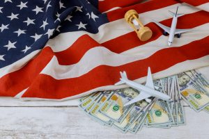 US flag with airplanes, cash, and hourglass symbolizing trade tariffs impact on aviation industry costs